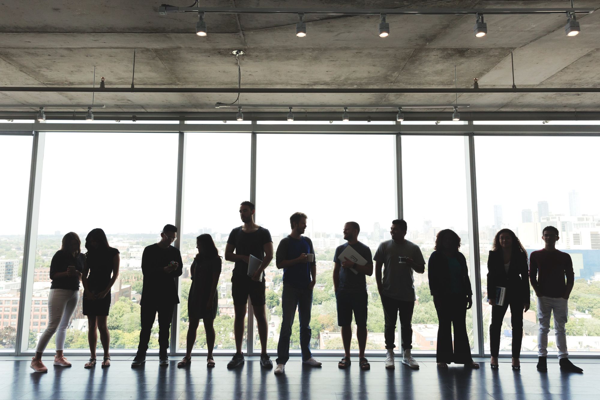 Eleven people standing in front of large backlit glass windows